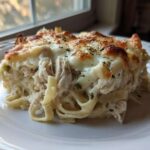 A generous serving of Creamy Alfredo Chicken Bake Easy Comfort Meal with melted, browned cheese topping.