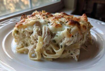 A generous serving of Creamy Alfredo Chicken Bake Easy Comfort Meal with melted, browned cheese topping.
