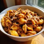 A close-up of a white bowl filled with Creamy Beef and Shells Pasta Quick Dinner, topped with melted cheese.