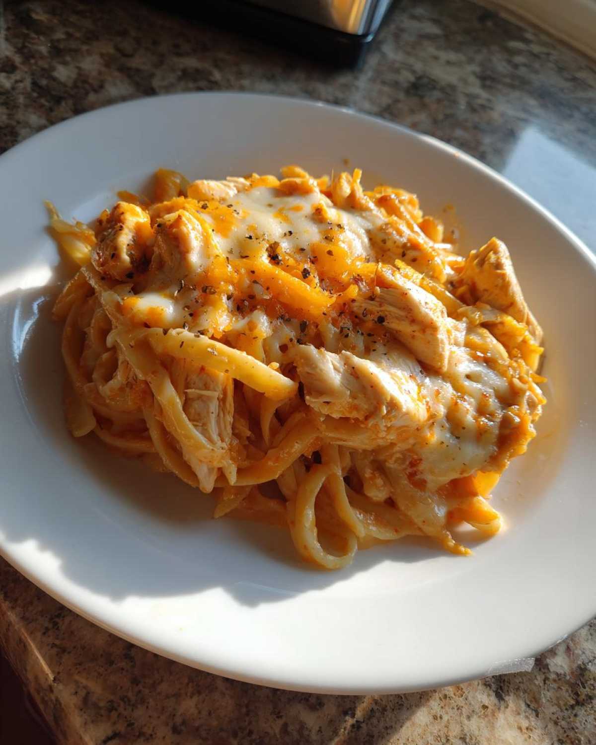A serving of Creamy Cajun Chicken Alfredo Bake with melted cheese and chicken pieces on a white plate.