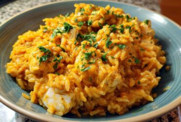 A close-up of a generous serving of Creamy Cajun Chicken Rice One Pot Meal, topped with fresh parsley, in a teal bowl.