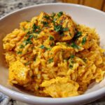 Close-up of a bowl filled with creamy Cajun chicken rice one pot meal, topped with seasoned chicken pieces and fresh parsley.