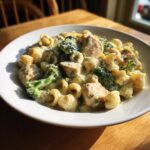 A white bowl filled with Creamy Chicken and Broccoli Pasta Dinner, featuring chunks of chicken, bright green broccoli florets, and pasta in a rich sauce.