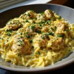 A close-up of a bowl filled with Creamy Garlic Parmesan Orzo with Chicken, topped with fresh parsley.