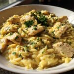 A close-up of Creamy Garlic Parmesan Orzo with Chicken, topped with fresh parsley, served in a white bowl.