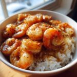 Close-up of a white bowl filled with white rice topped generously with succulent Creamy Garlic Shrimp.