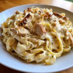 Close-up of creamy Honey Garlic Chicken Pasta with fettuccine noodles, topped with seared chicken pieces and grated cheese.