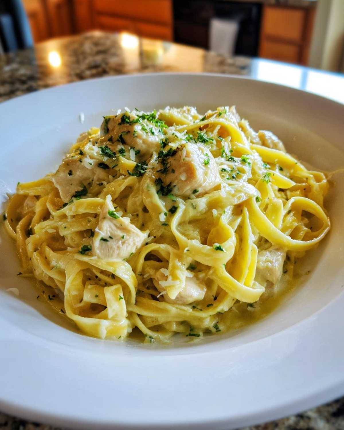 Close-up of Creamy Lemon Chicken Pasta with Parmesan featuring fettuccine, chicken pieces, and parsley garnish.