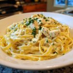 Close-up of rich Creamy Lemon Chicken Pasta with Parmesan, featuring fettuccine noodles coated in sauce and topped with diced chicken and parsley.