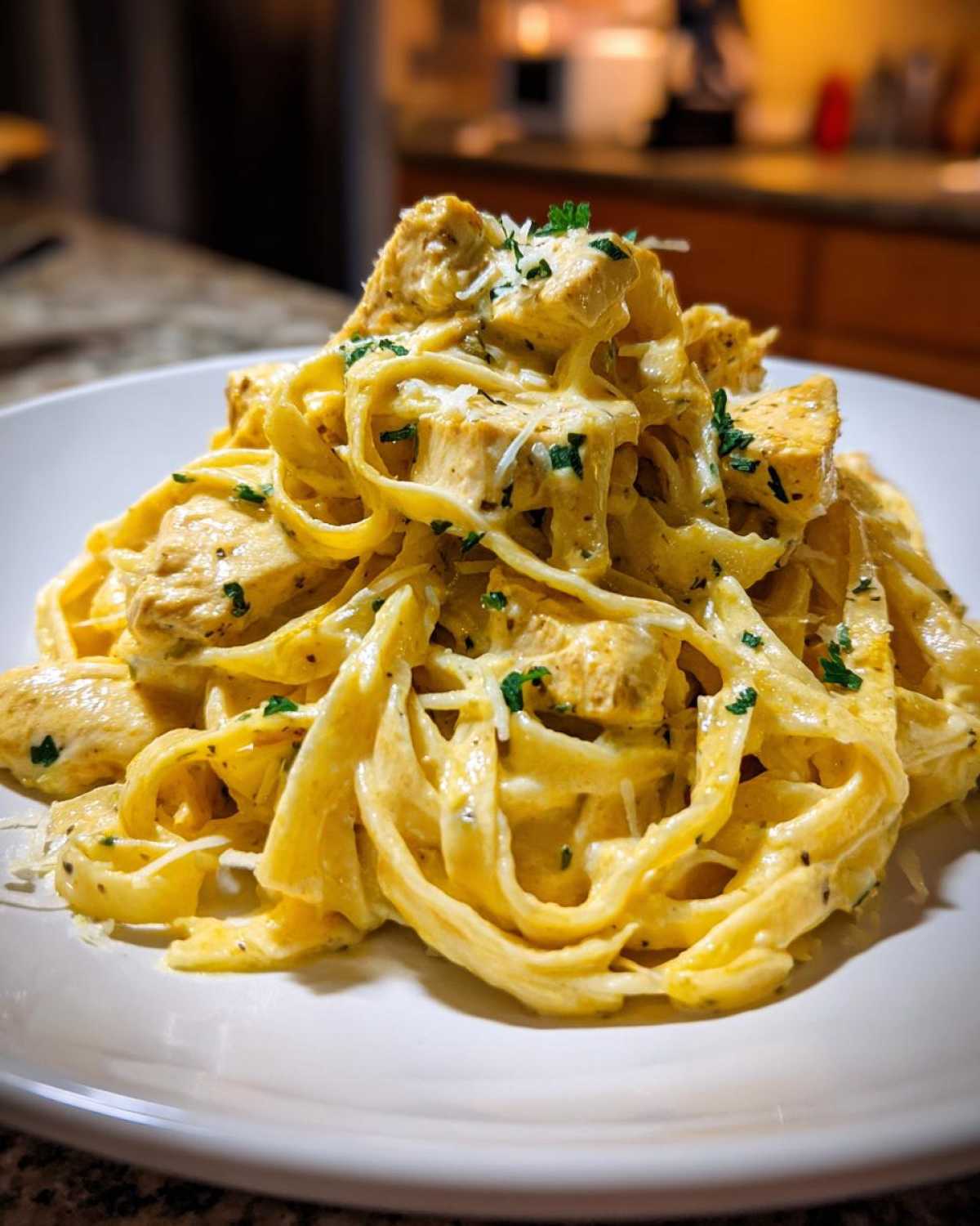 A close-up of a generous serving of Creamy Lemon Chicken Pasta with Parmesan, garnished with fresh parsley.