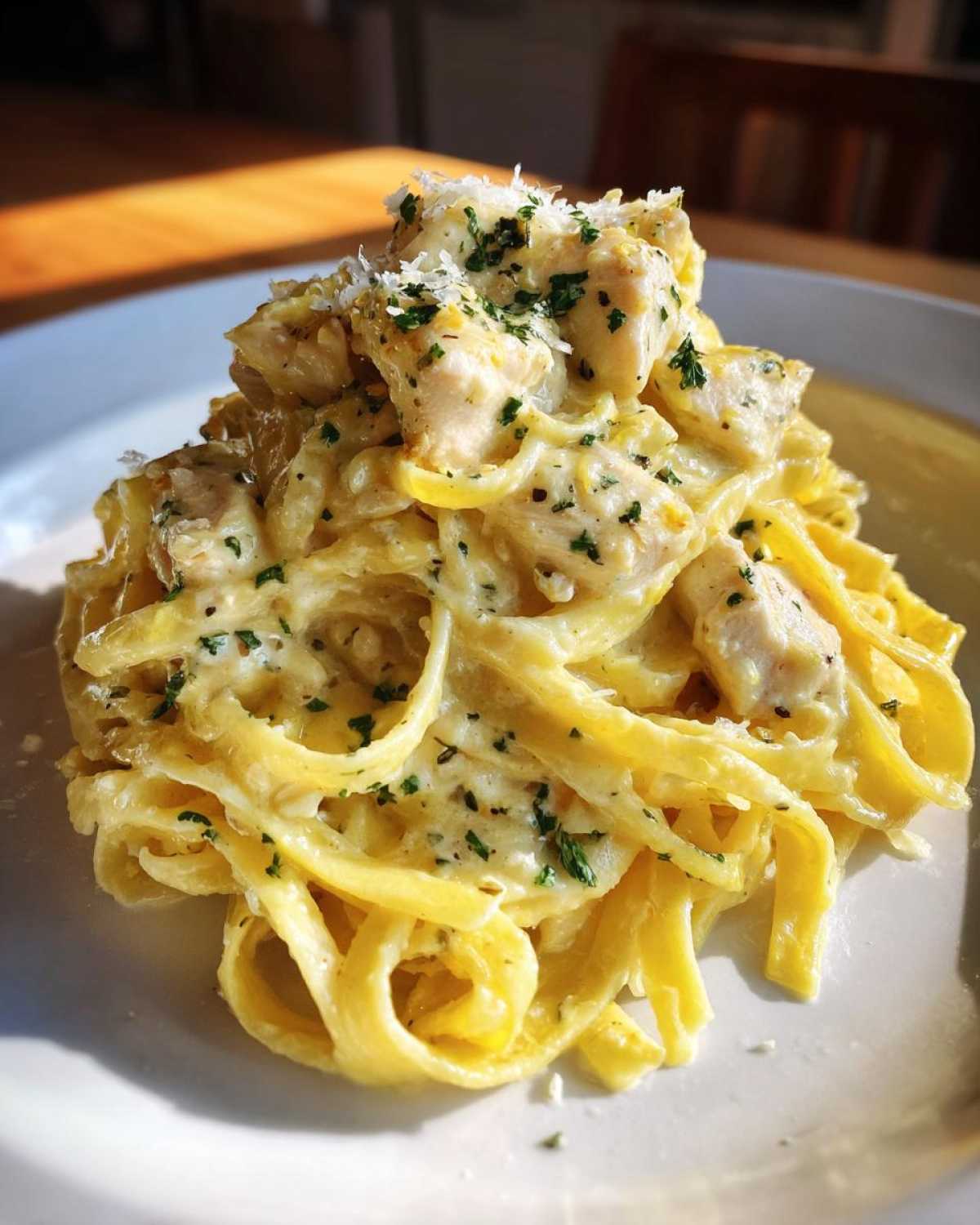 Close-up of creamy lemon chicken pasta with parmesan cheese and parsley garnish.