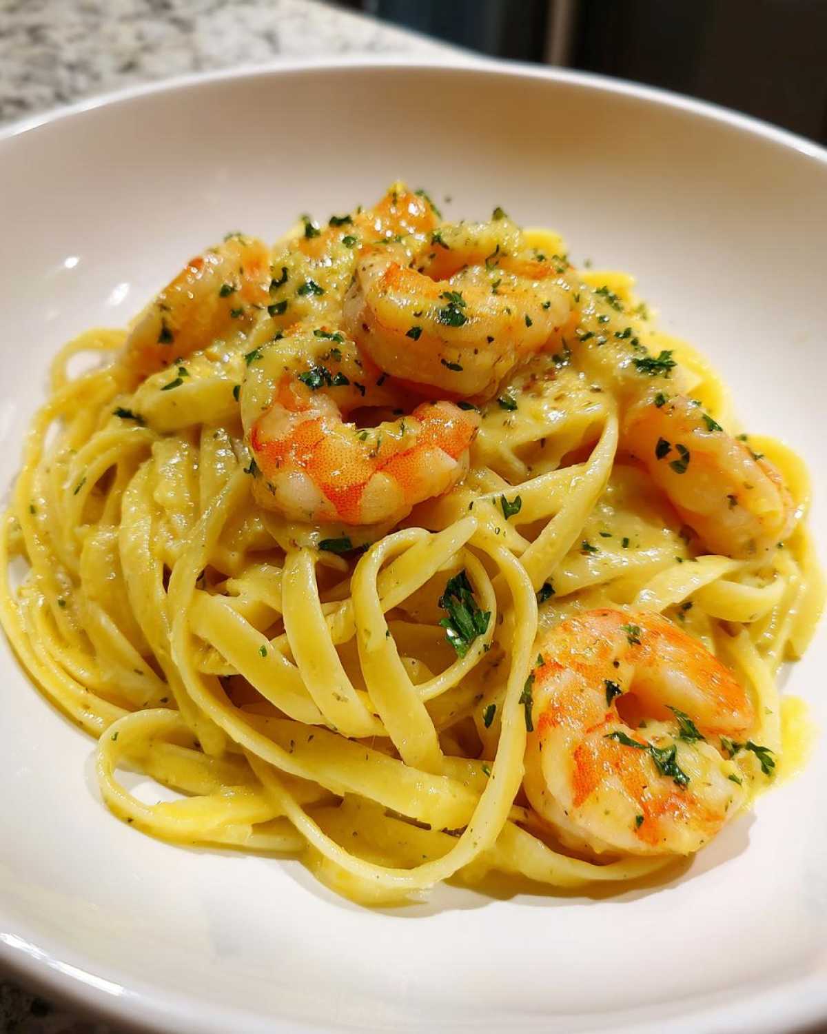 Close-up of Creamy Lemon Garlic Shrimp Pasta with fettuccine noodles and pink shrimp, garnished with parsley.