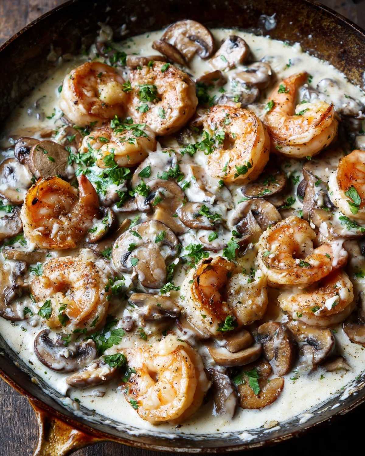 Close-up of perfectly cooked shrimp and sliced mushrooms swimming in a rich, creamy sauce in a skillet, part of the Creamy Mushroom Alfredo Shrimp Skillet.