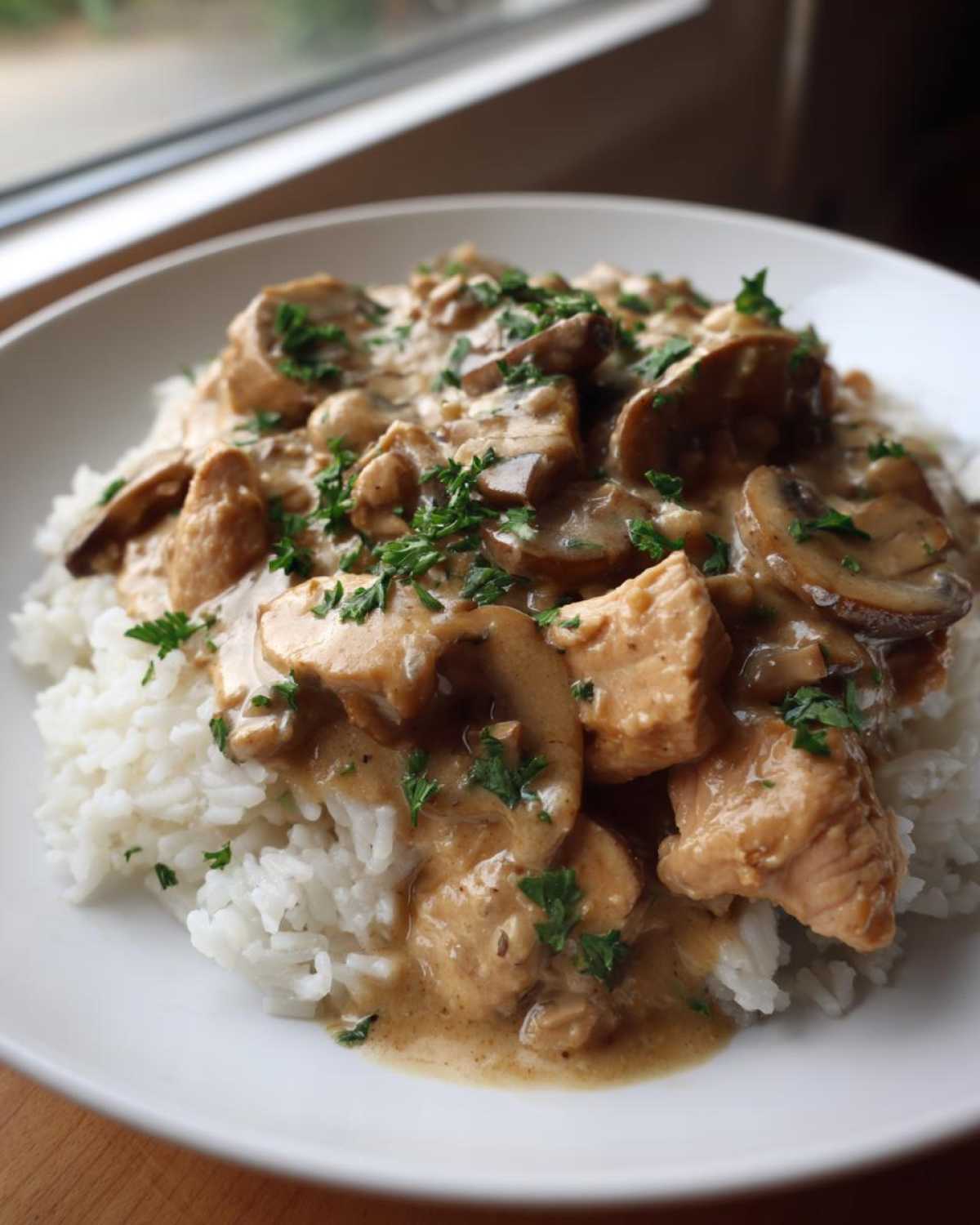 A close-up of Creamy Mushroom Chicken and Rice Skillet served over white rice, topped with fresh parsley.