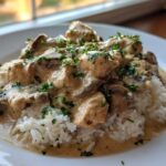 A close-up of Creamy Mushroom Chicken and Rice Skillet served over white rice, topped with fresh parsley.