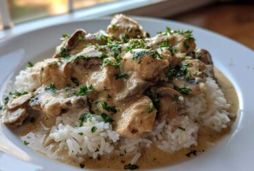 A close-up of Creamy Mushroom Chicken and Rice Skillet served over white rice, topped with fresh parsley.