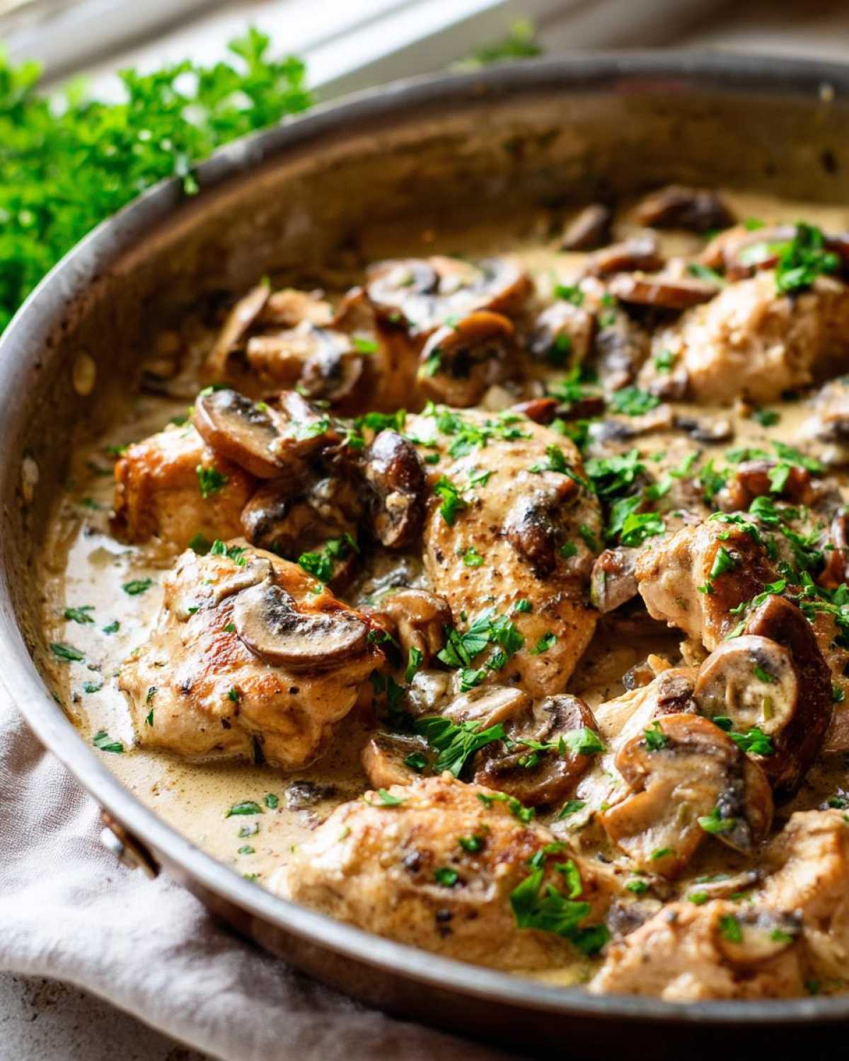 Close-up of seared chicken pieces smothered in a rich, creamy mushroom sauce, garnished with fresh parsley for a Creamy Mushroom Chicken Skillet.