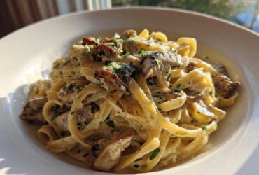 A close-up of fettuccine pasta coated in a rich, creamy mushroom sauce and garnished with fresh parsley, showcasing the Creamy Mushroom Pasta with Parmesan Sauce.