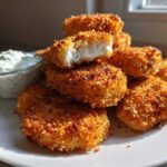 A stack of golden brown Crispy Chicken Nuggets with Ranch Dip served on a white plate.
