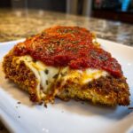 A close-up of a slice of Crispy Chicken Parmesan with Melty Cheese, featuring a golden crust, stretching mozzarella, and rich tomato sauce.