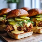 A close-up of a Crispy Chicken Sliders with Honey Mustard, topped with pickles and fresh dill.