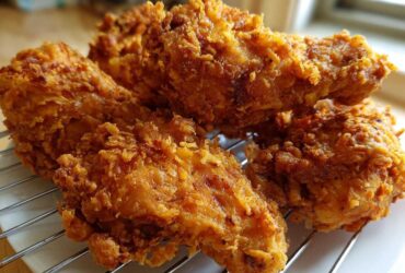 Four pieces of perfectly cooked Crispy Fried Chicken with Golden Crunch resting on a wire cooling rack.