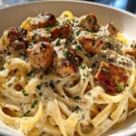 Close-up of rich Garlic Butter Chicken Pasta with fettuccine noodles coated in a creamy sauce and topped with seared chicken pieces.