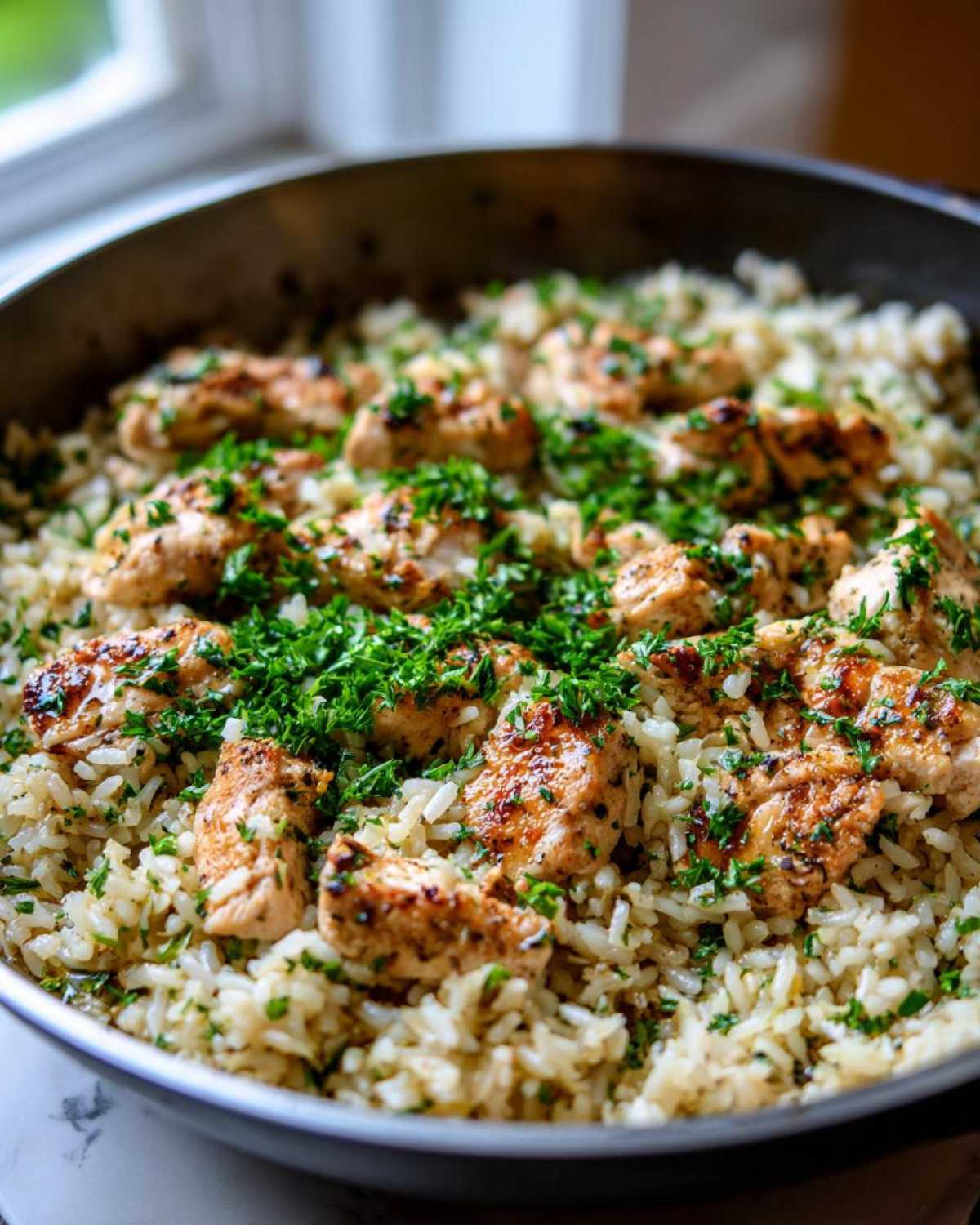 Close-up of Garlic Butter Rice with Chicken Skillet, topped with fresh parsley.
