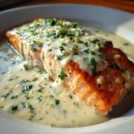 A perfectly cooked fillet of Garlic Butter Salmon smothered in creamy lemon sauce and topped with fresh parsley.