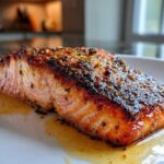 Close-up of a perfectly cooked fillet of Garlic Butter Salmon with Crispy Skin Recipe, glistening with butter sauce.