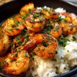 Close-up of succulent Garlic Butter Shrimp and Rice served in a black bowl, topped with fresh parsley.