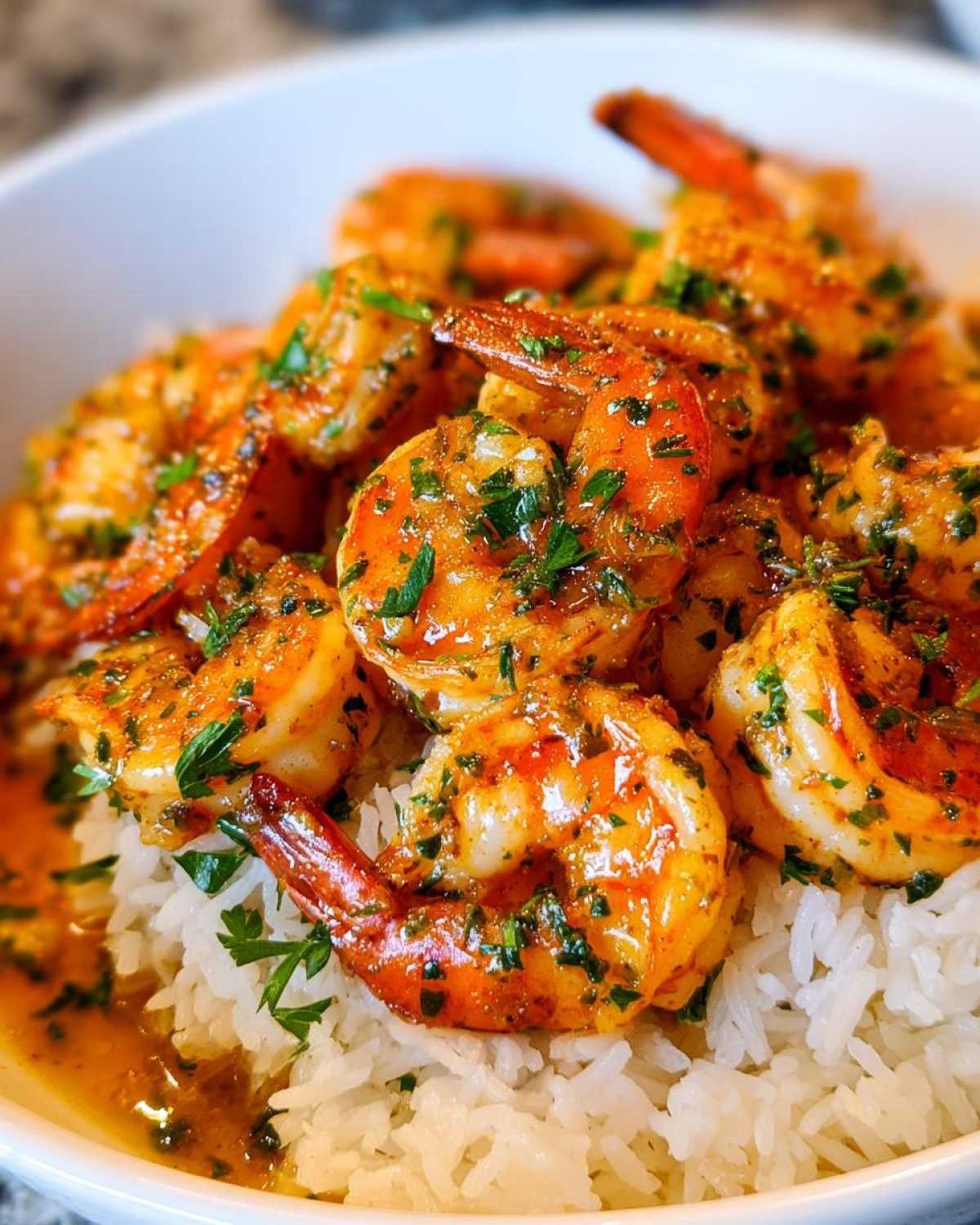 Close-up of juicy, orange Garlic Butter Shrimp and Rice Easy Recipe topped with fresh parsley.