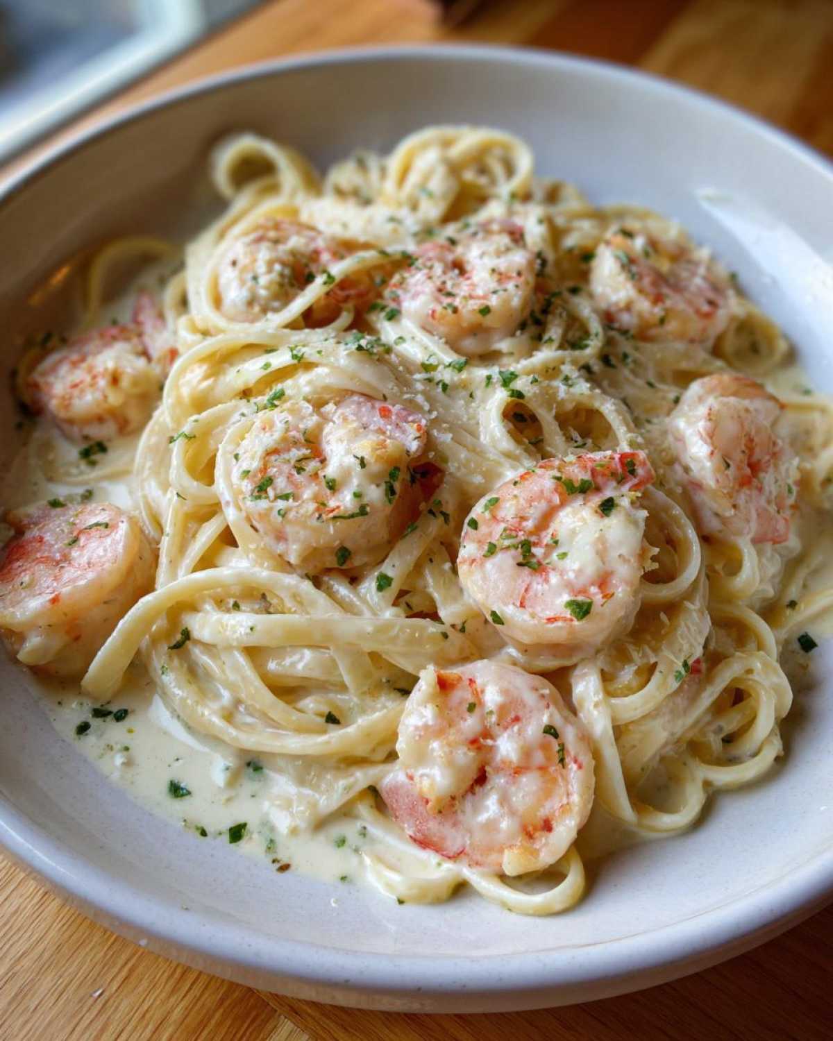 Close-up of rich Garlic Butter Shrimp Pasta with Cream Sauce, topped with large shrimp and fresh parsley.