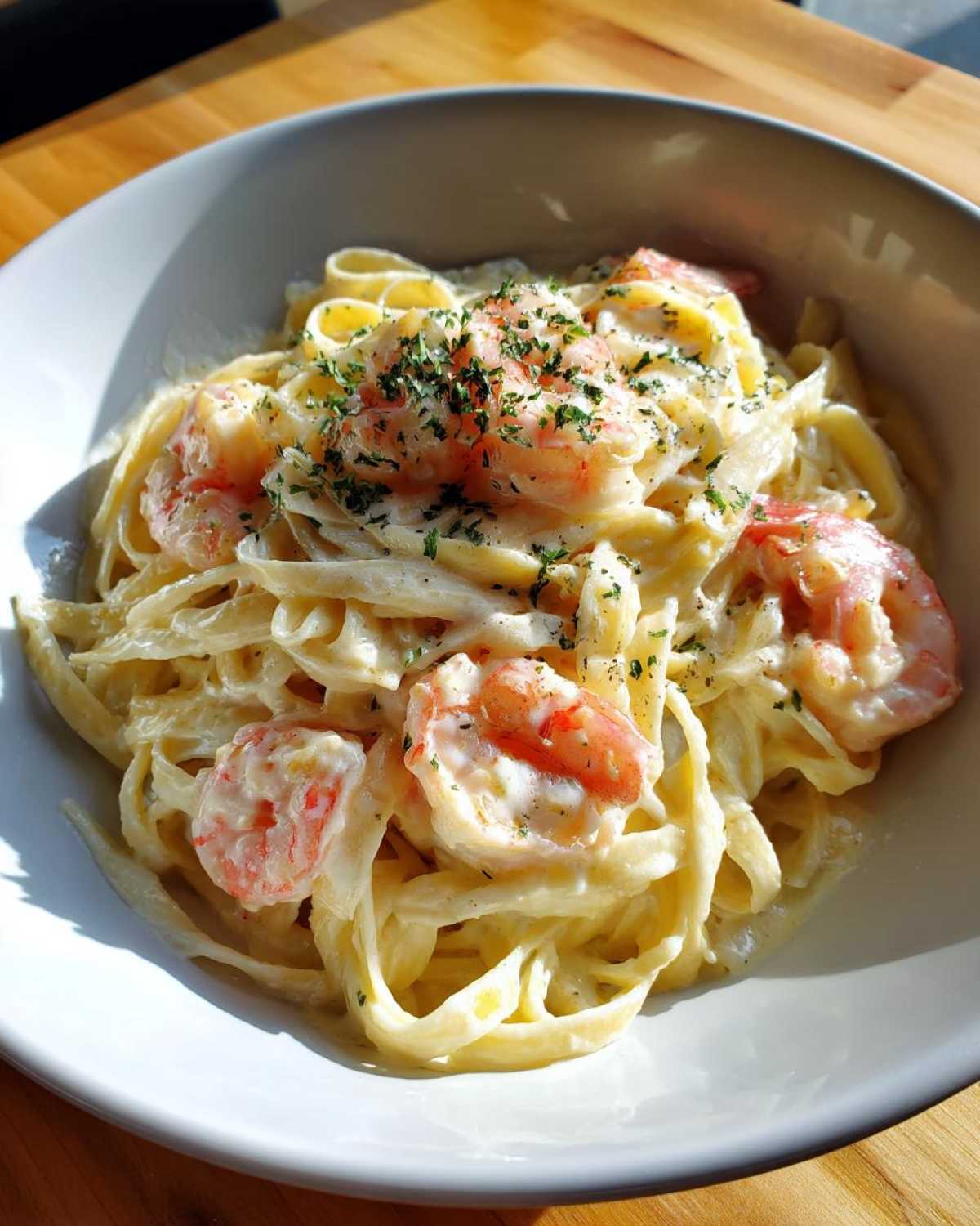 Close-up of creamy Garlic Butter Shrimp Pasta with fettuccine noodles and pink shrimp, topped with parsley.