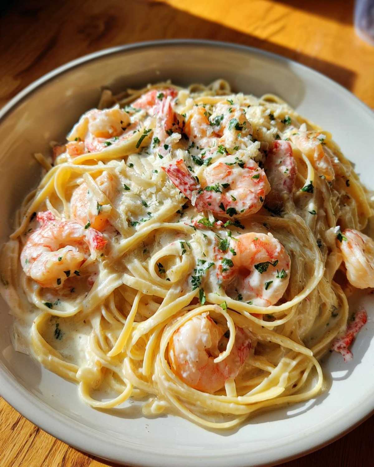 Close-up of fettuccine pasta tossed in a rich cream sauce with pink shrimp, topped with Parmesan and parsley for Garlic Butter Shrimp Pasta.