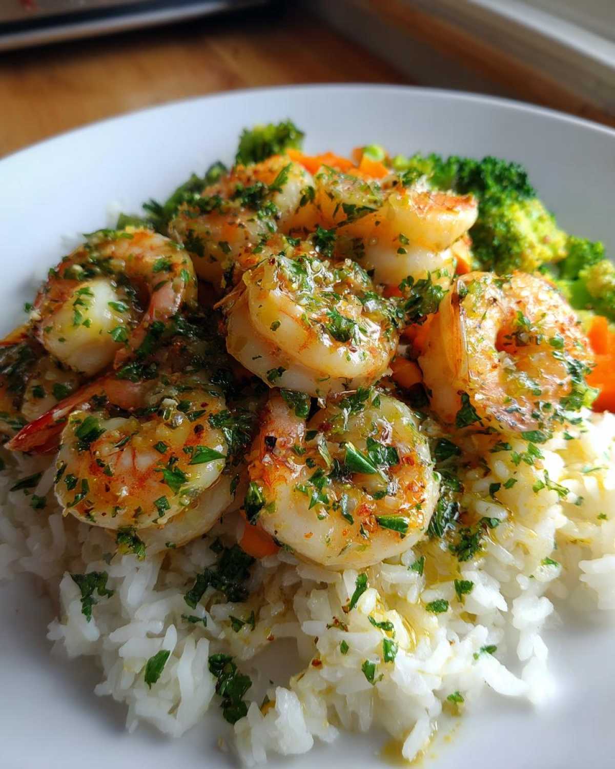Close-up of Garlic Butter Shrimp with Rice and Veggies, glistening with butter sauce and parsley.