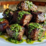Close-up of seared Garlic Butter Steak Bites piled high and drizzled with bright green herb sauce.