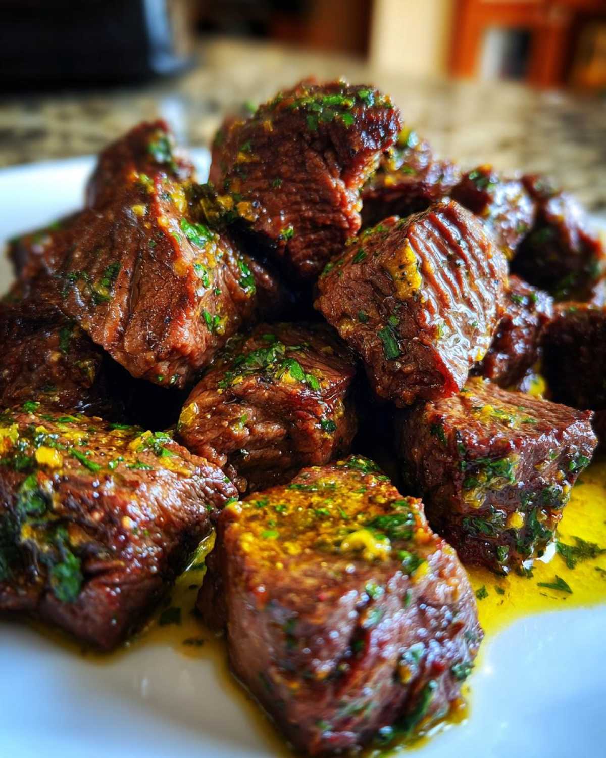 Close-up of tender Garlic Butter Steak Bites coated in rich, yellow garlic butter sauce and fresh green parsley.
