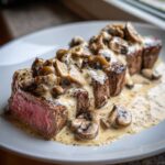 Close-up of perfectly cooked Garlic Butter Steak with Creamy Mushroom Sauce poured over tender, medium-rare slices.