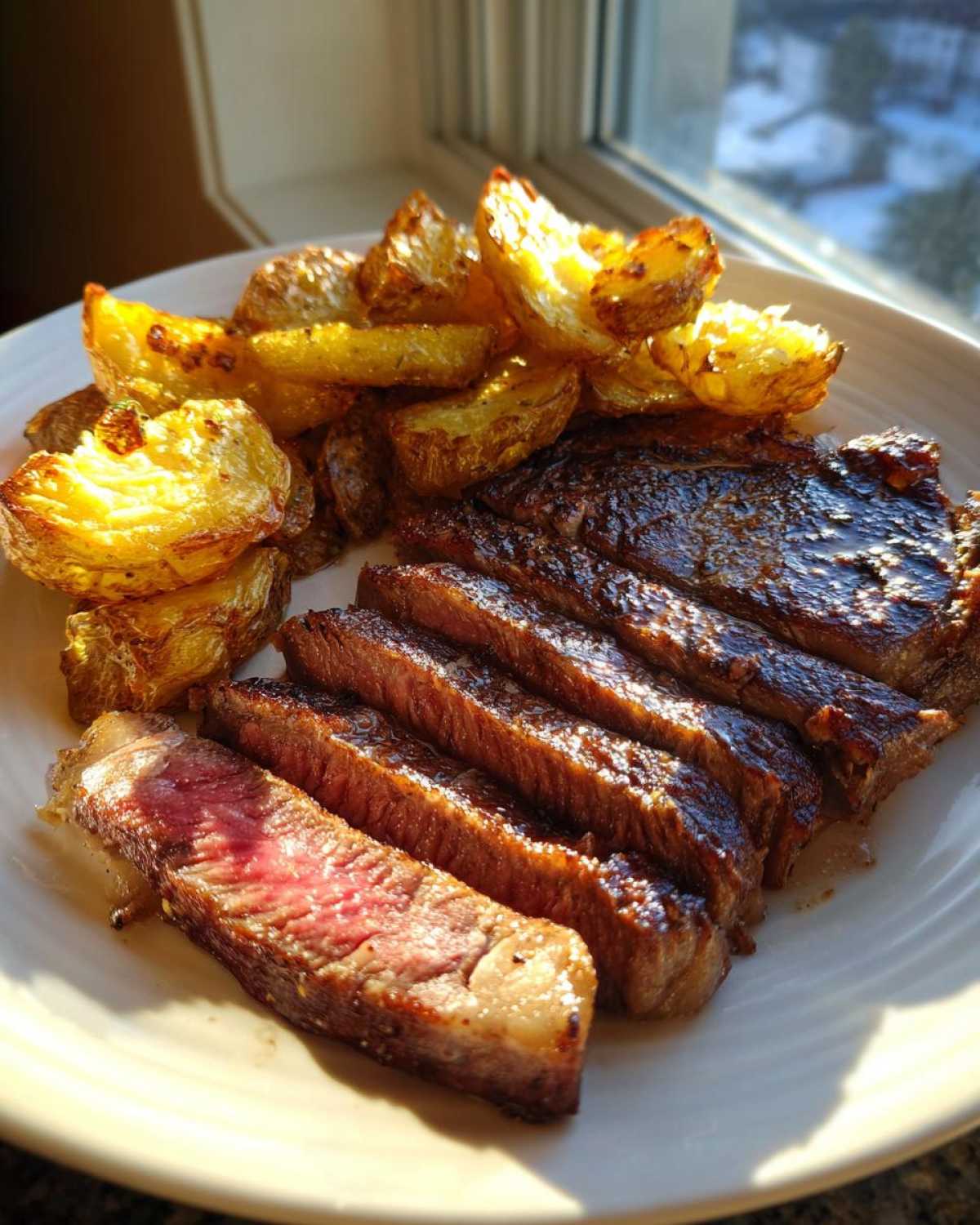 Perfectly cooked Garlic Butter Steak, sliced medium-rare, served alongside golden crispy potatoes.