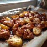 Close-up of Honey BBQ Chicken Bake with Potatoes glistening with sauce on parchment paper.