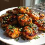 Close-up of golden-brown Honey Butter Garlic Salmon Bites, glazed and topped with fresh chopped parsley, served on a white plate.