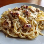 A close-up shot of fettuccine pasta coated in a rich cream sauce, topped with seared chicken pieces from the Honey Garlic Chicken Pasta.