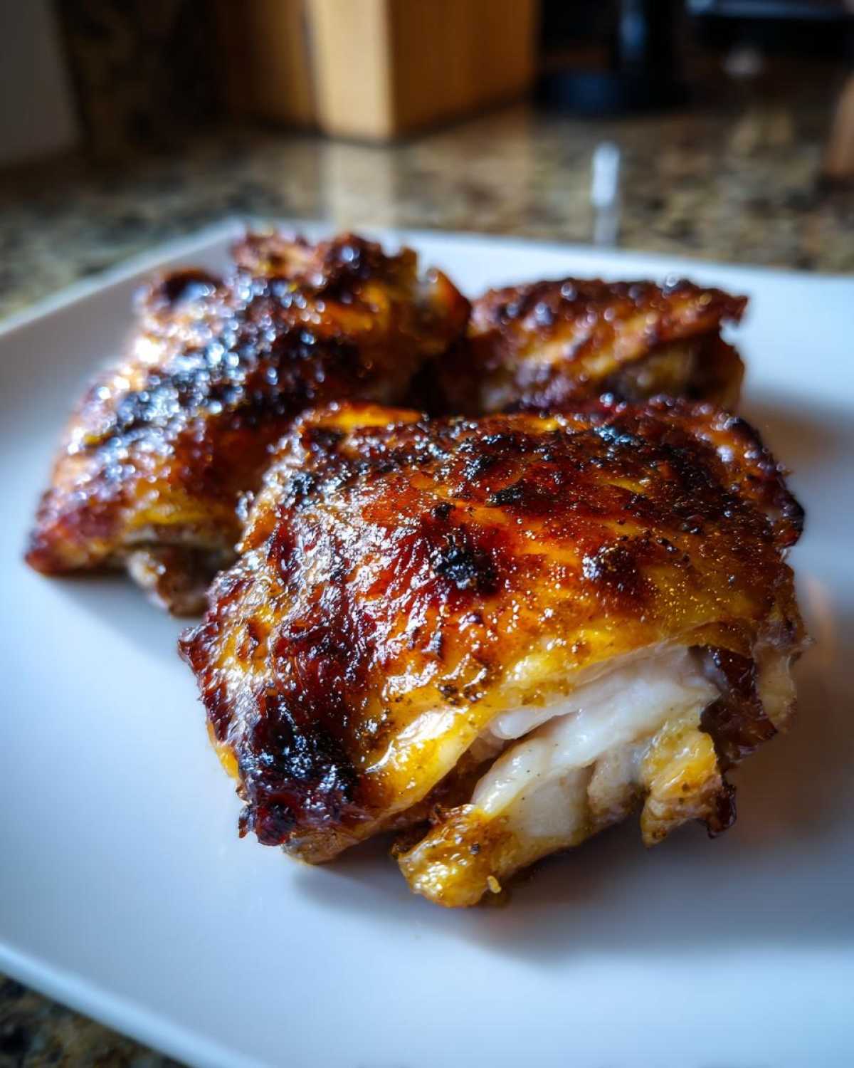 Close-up of juicy Honey Mustard Chicken Thighs Oven Roasted with a caramelized, dark glaze on a white plate.