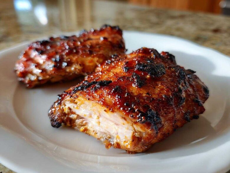Two pieces of perfectly caramelized Honey Mustard Chicken Thighs Oven Roasted served on a white plate.
