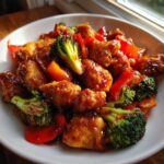 Close-up of Honey Soy Chicken Skillet with Veggies featuring glazed chicken pieces, bright green broccoli florets, and red bell peppers in a white bowl.