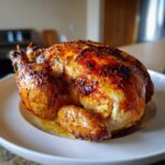 A whole, perfectly roasted Lemon Herb Roasted Chicken with deeply browned, crispy skin resting on a white serving platter.