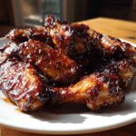 A plate piled high with glistening Sticky BBQ Chicken Wings with Honey Glaze, catching the sunlight.