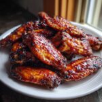 A pile of glistening, caramelized Sticky Honey Garlic Wings Oven Baked served on a white plate.
