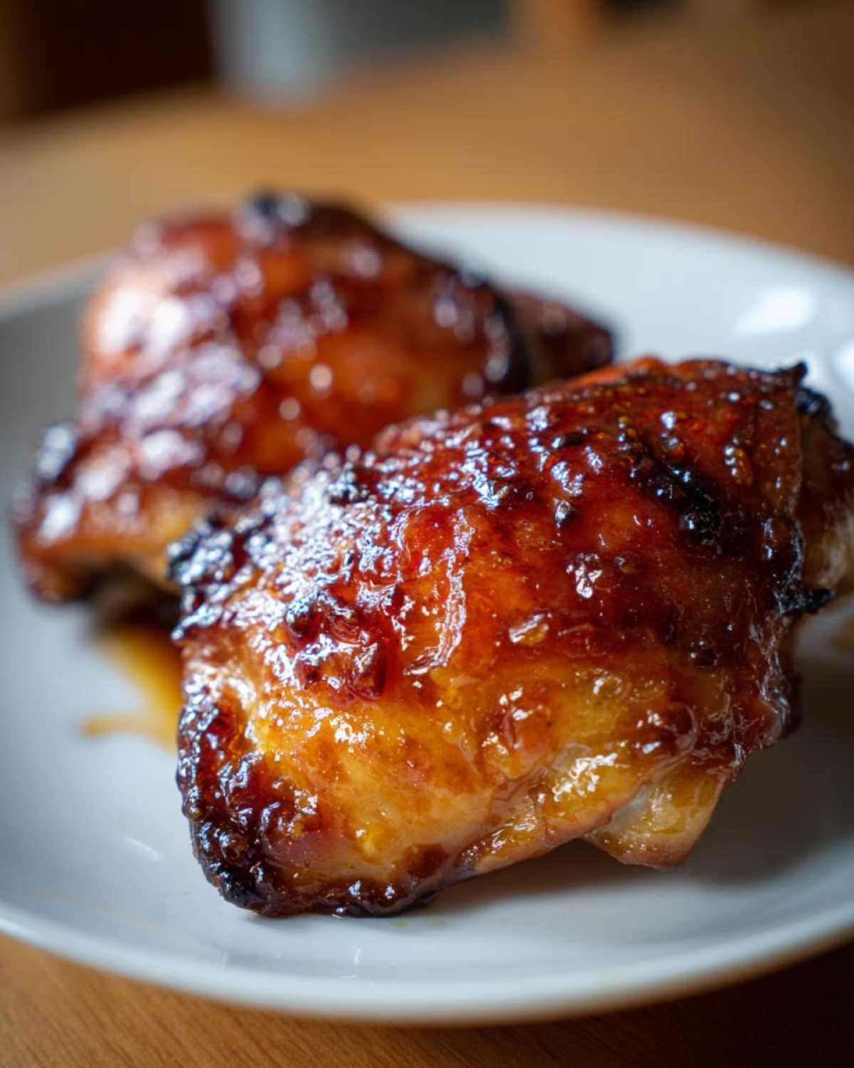 Two oven-baked chicken thighs coated in a thick, glossy, caramelized sweet chili glaze.